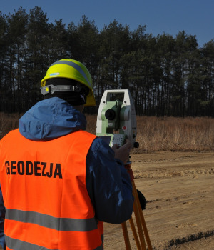 Zdjęcie przedstawia geodetę z tachimetrem